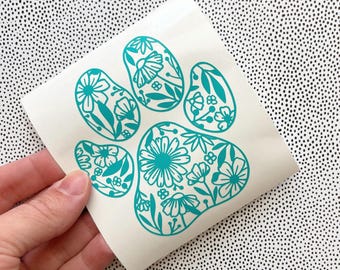 May include: Teal paw print decal with a floral design. The paw print is made up of five individual flower shapes.