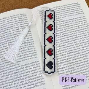 May include: Handmade bookmark with a white background and a repeating pattern of red hearts and black spades. A white tassel hangs from the top. The text "PDF Pattern" is visible.