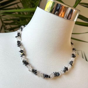 May include: A black and clear crystal necklace featuring geometric shapes. The necklace is made of small, faceted stones and is strung on a thin cord.