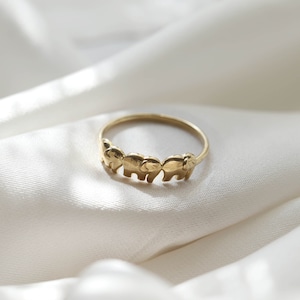 Op de afbeelding: Een gouden ring met een ontwerp van vijf olifanten die in een rij lopen.