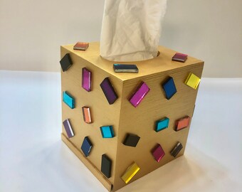 Könnte beinhalten: Goldene Taschentuchbox mit bunten quadratischen Verzierungen.