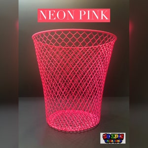 Puede incluir: Un cubo de basura de rejilla de alambre de color rosa ne&oacute;n brillante. El cubo tiene forma de cono y presenta un patr&oacute;n de diamante.