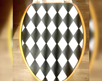 May include: A black and white diamond patterned toilet seat cover with a gold trim.