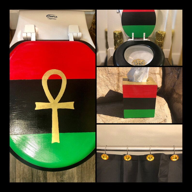 May include: A bathroom decor set featuring a toilet seat, tissue box, and shower curtain. The toilet seat and tissue box are painted with red, black, and green stripes, and a gold ankh symbol. The shower curtain has gold-colored shower curtain rings.