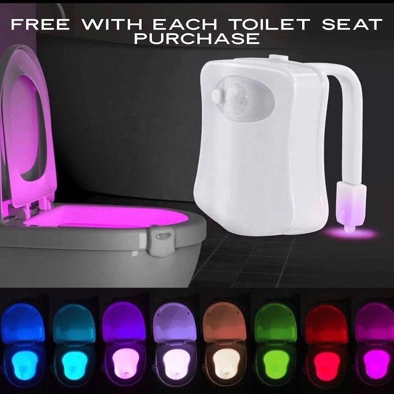 May include: A white LED toilet night light with a motion sensor. The toilet seat is illuminated with a pink glow. The image also shows a variety of colors the light can display, including blue, green, and red. Text on the image reads "FREE WITH EACH TOILET SEAT PURCHASE".