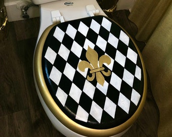 May include: A black and white checkered toilet seat cover with a gold fleur-de-lis design.