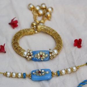 Um conjunto de Bhaiya Bhabhi Rakhi enviado em uma linda CAIXA festiva com cartão de cortesia e pacote Roli Chawal