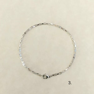 May include: A silver chain bracelet with a box chain design and a lobster clasp.