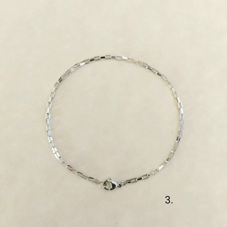 May include: A silver chain bracelet with a box chain design and a lobster clasp.
