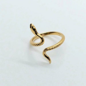 May include: A gold-toned snake ring with a textured finish. The snake is coiled around the ring band, with its head raised and facing forward.