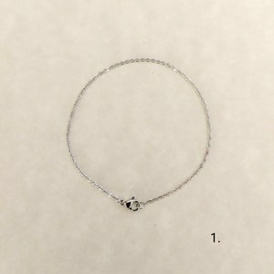 May include: A silver chain necklace with a lobster clasp.