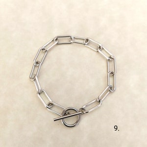 May include: A silver chain bracelet with a toggle clasp. The chain is made of oval links.