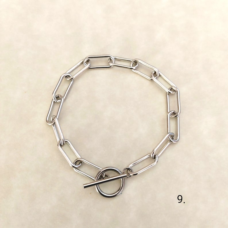 May include: A silver chain bracelet with a toggle clasp. The chain is made of oval links.