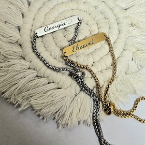 May include: Two personalised bracelets. One is silver-toned with the name "Georgia" and a heart, the other is gold-toned with the name "Elisavet" and a heart. Both bracelets have adjustable chain links.