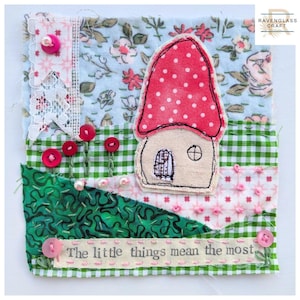 May include: A fabric collage featuring a red and white polka-dot mushroom house appliqué on a background of floral, green gingham, and patterned textiles. Embellished with pink buttons, white beads, and a strip with the text The little things mean the most.