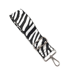 May include: A black and white zebra print adjustable strap with a silver metal clasp and a silver metal loop.