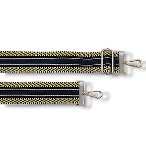 May include: A black and yellow striped fabric strap with silver metal clasps and hooks. The strap is designed for a bag or purse.