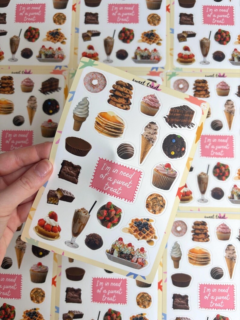 May include: A sheet of colourful stickers featuring various desserts such as doughnuts, cupcakes, ice cream cones, and chocolate candies. The stickers have the text "I'm in need of a sweet treat" and "sweet treat".
