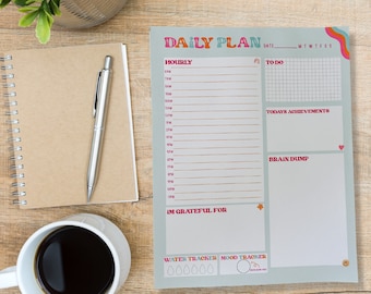May include: A light blue daily planner with a rainbow design. The planner has sections for hourly scheduling, to-do lists, today's achievements, brain dump, and gratitude. It also includes a water tracker and mood tracker.