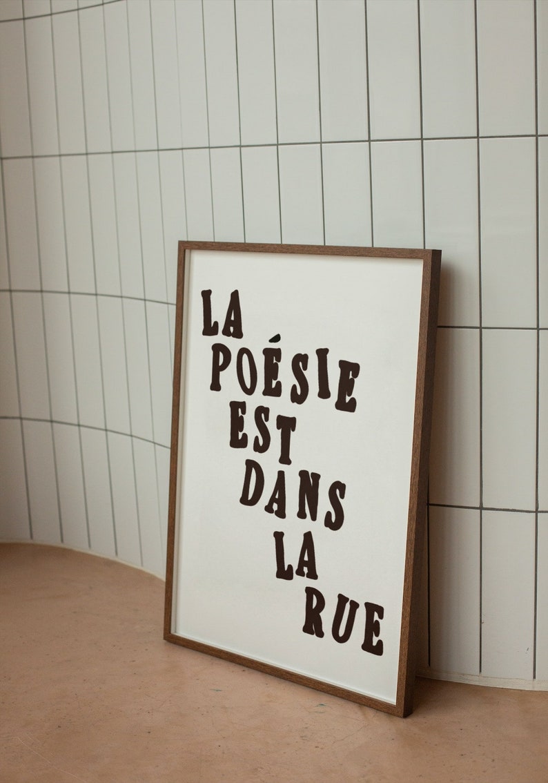 Puede incluir: Una impresi&oacute;n enmarcada con el texto "LA PO&Eacute;SIE EST DANS LA RUE" en letras negras sobre un fondo blanco.
