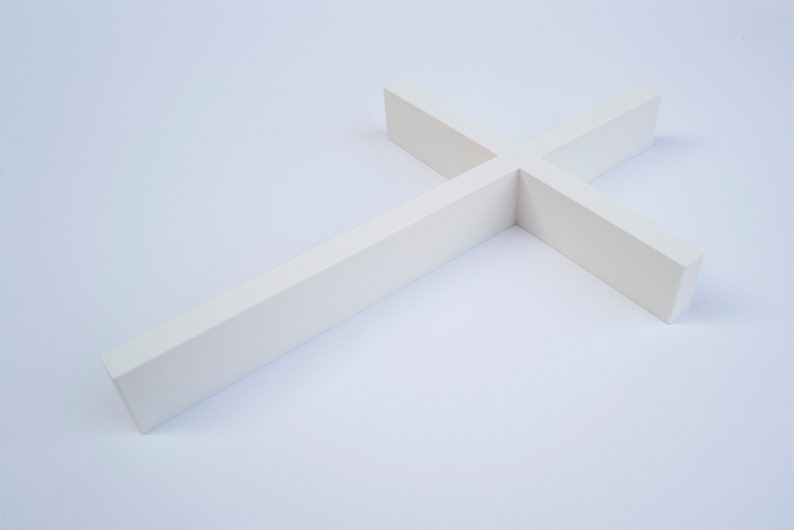 Peut inclure: Une croix blanche en bois pos&eacute;e &agrave; plat sur une surface blanche.