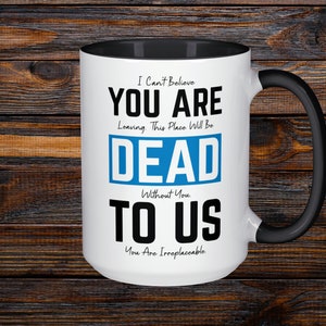 May include: White ceramic mug with a black interior and handle. The mug features the text "I Can't Believe YOU ARE Leaving This Place Will Be DEAD TO US You Are Irreplaceable" in black and blue font.