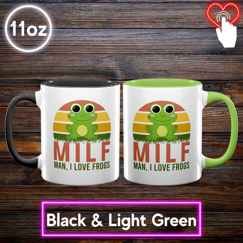 May include: Two 11oz ceramic mugs, one with a black handle and the other with a light green handle. Each mug features a green frog graphic with the text "MILF MAN, I LOVE FROGS" against a sunset background. The bottom text reads "Black & Light Green".