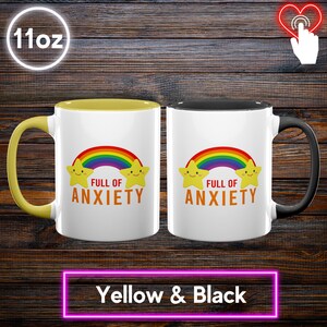 May include: Two 11oz white ceramic mugs with the text "FULL OF ANXIETY" under a rainbow and star design. One mug has a yellow interior and handle, the other has a black interior and handle. The bottom of the image reads "Yellow & Black".
