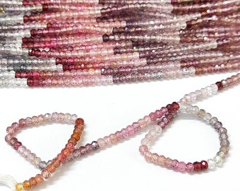 May include: A strand of pink, red, and clear faceted gemstone beads. The beads are strung on a white thread and are arranged in a graduated pattern. The beads are approximately 2mm in diameter.