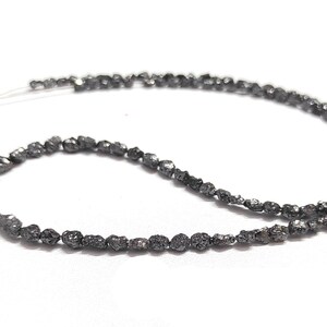 May include: A strand of black diamond beads, strung on a thin wire. The beads are irregular in shape and have a rough, unpolished texture.