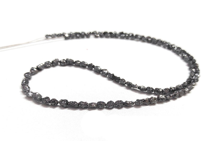 May include: A strand of black diamond beads, strung on a thin wire. The beads are irregular in shape and have a rough, unpolished texture.
