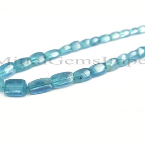 May include: A strand of light blue aquamarine gemstone beads. The beads are faceted and have a rectangular shape. The beads are strung on a clear thread.