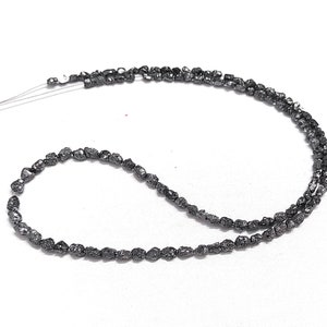 May include: A strand of black rough diamond beads, strung on a thin wire.