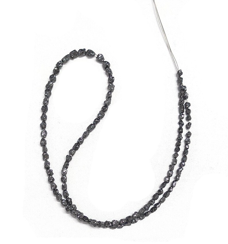 May include: A strand of black rough diamond beads, strung on a thin wire. The beads are irregular in shape and have a matte finish.