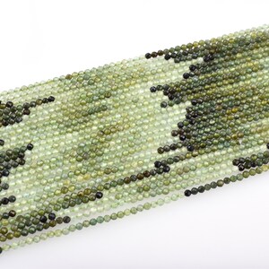 May include: A strand of green gemstone beads, each bead is round and faceted. The beads are strung on a clear thread and are ready for jewelry making.