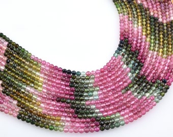 May include: A strand of multi-colored round gemstone beads. The beads are a mix of pink, green, and blue.