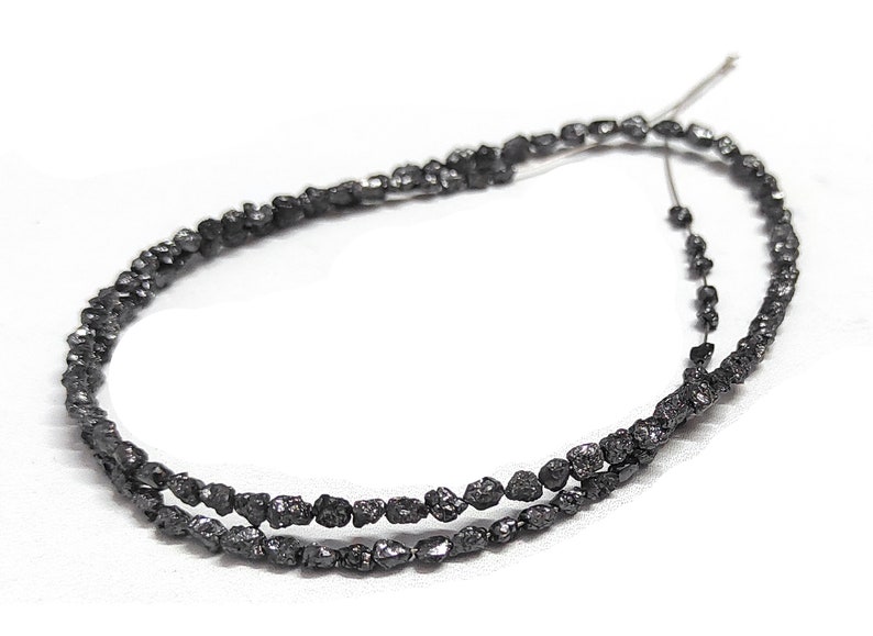 May include: A strand of black diamond beads, each bead is a rough, uncut diamond. The beads are strung on a thin wire and are ready to be used in jewelry making.