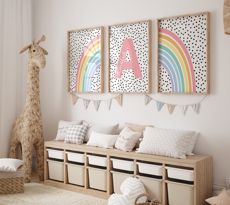 May include: Three framed prints featuring a rainbow and polka dot design. The centre print has the letter "A" in a pink box with the name "Amelia" written above it.