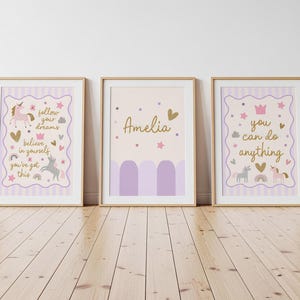 May include: Three framed art prints with a whimsical theme. The prints feature unicorns, rainbows, and encouraging phrases like "follow your dreams" and "you can do anything." The color palette includes soft purples, gold accents, and a light beige background.
