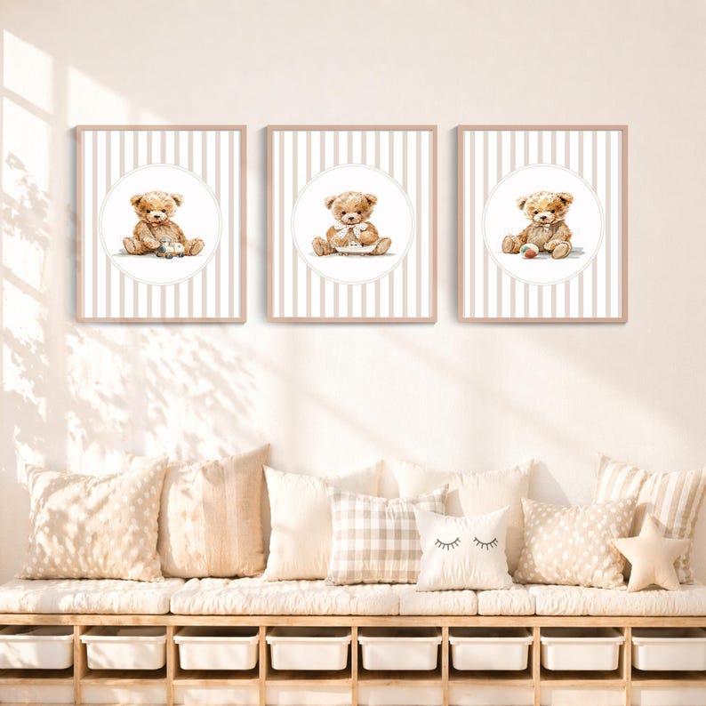May include: Three framed prints featuring watercolor illustrations of teddy bears. Each bear is seated within a white circle against a backdrop of vertical beige stripes. The frames are a light beige color, and the overall theme is a nursery or children's room.