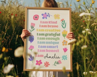 May include: A framed print with the words "I am Kind, I am brave, I am creative, I am grateful, I am enough, I am unique, I am smart, I am honest, I am Amelia" surrounded by colorful floral illustrations. The frame is a light brown color.