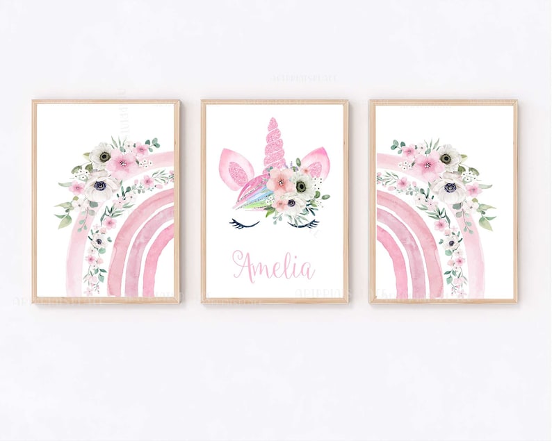 May include: Three watercolour prints featuring a pink rainbow with white flowers, a unicorn face with a floral crown, and the name Amelia.