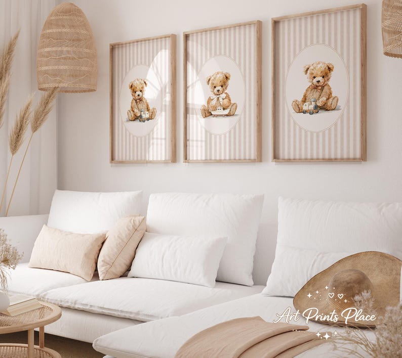 May include: Three framed art prints featuring watercolor illustrations of teddy bears. Each print has a light brown wooden frame and a background with vertical stripes. The teddy bears are depicted in various poses, with soft brown fur and seated on a white oval.