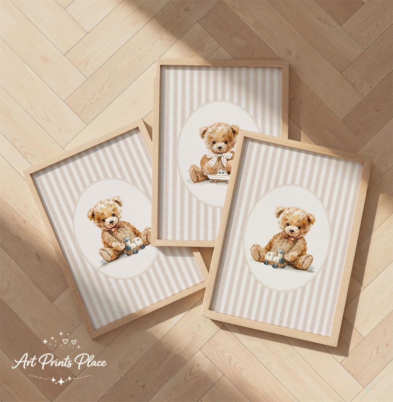 May include: Three framed prints featuring watercolor illustrations of teddy bears. Each bear is depicted with a vintage toy or bow tie, set against a striped background within a light wood frame. The prints are arranged on a wooden floor.