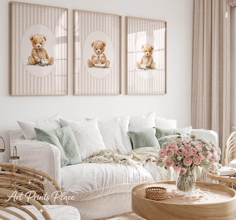 May include: Three framed art prints featuring watercolor teddy bears. Each print has a beige striped background with an oval containing a teddy bear illustration. The bears are light brown and have different accessories.