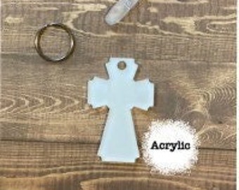 May include: White acrylic cross keychain with a silver key ring. The cross is a simple design with a slightly raised edge around the perimeter.  The word "Acrylic" is written in black below the cross.