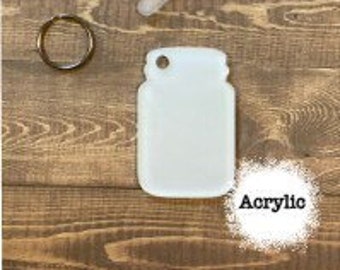 May include: White acrylic mason jar keychain with a metal ring and a small clear plastic scraper. The keychain is blank and ready to be customized.
