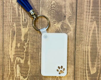 May include: White plastic keychain with a paw print design and a blue tassel.