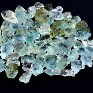 May include: A large pile of aquamarine gemstones, with a variety of shapes and sizes. The stones are a light blue-green color and have a translucent appearance.