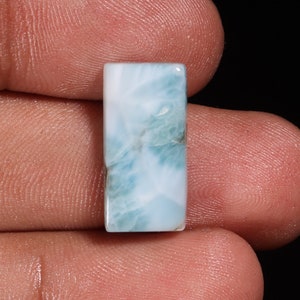 Könnte beinhalten: Ein rechteckiger, blauer Cabochon-Edelstein mit einem wolkigen, marmorierten Muster.